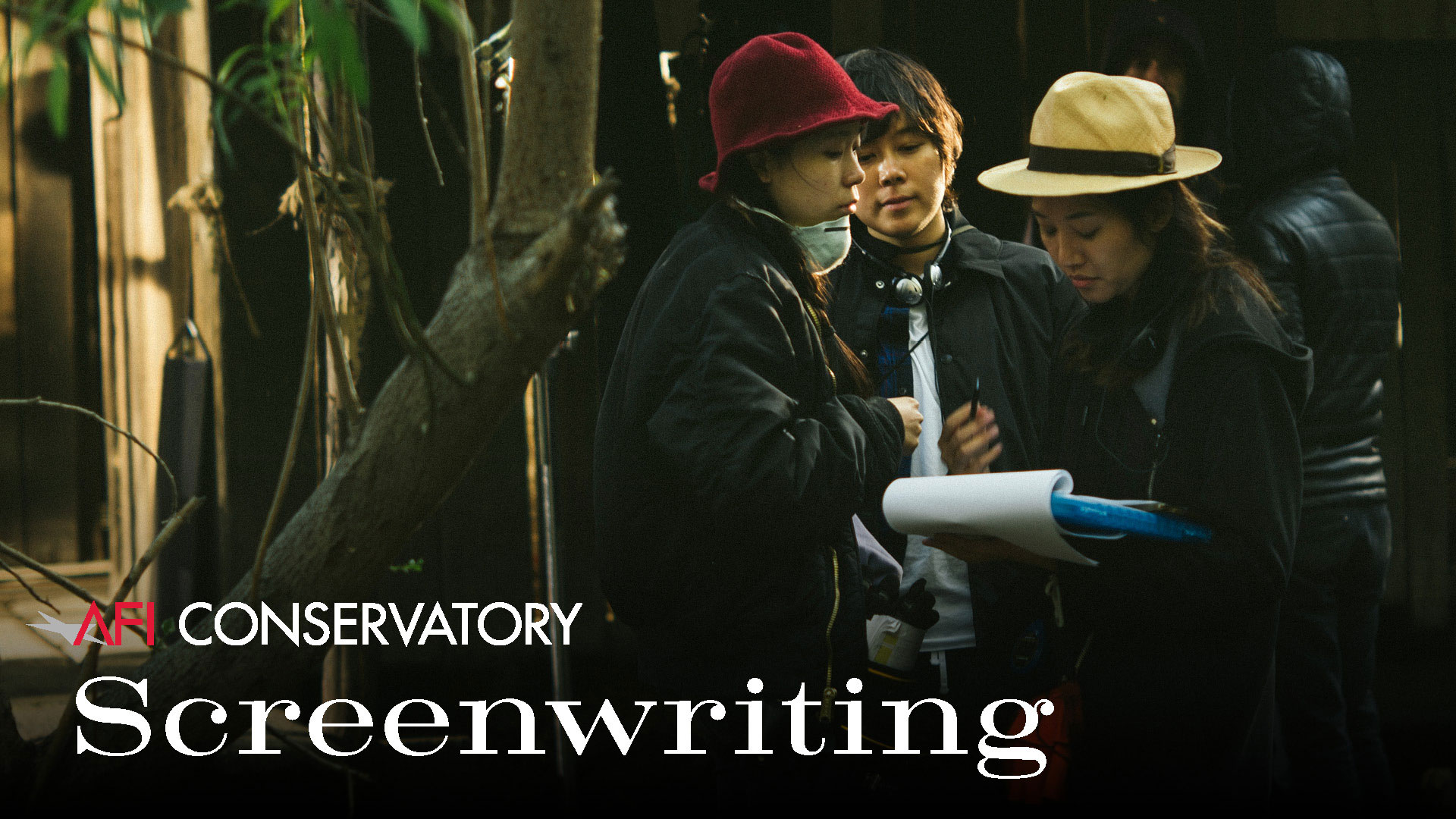 Three female filmmakers huddled together on an outdoor film set and discussing the script. Over the image, there is the following text: AFI Conservatory Screenwriting