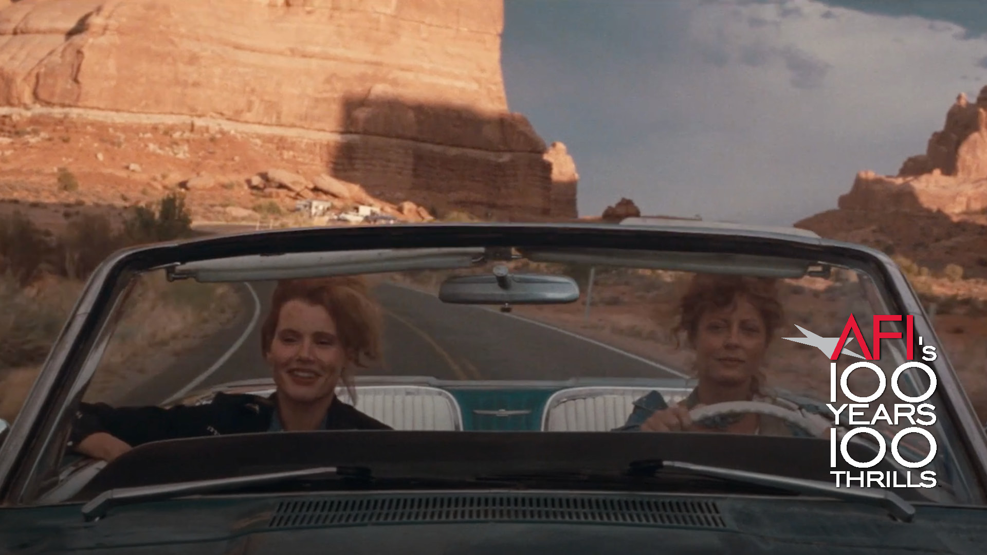 There is and AFI 100 Years...100 Movies logo in the lower righthand corner. The film still is from THELMA & LOUISE and shows the two main characters driving in their iconic convertible with red rock landscapes in the background.