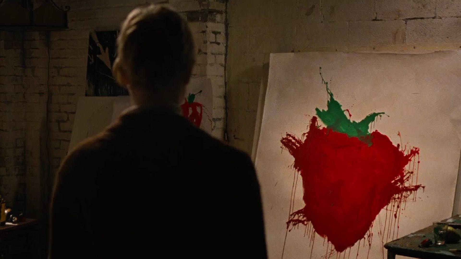ACROSS THE UNIVERSE film still of a man standing in front of a painting of a strawberry