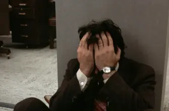 DOG DAY AFTERNOON film still of a man sitting on the floor of an office with his hands over his face.
