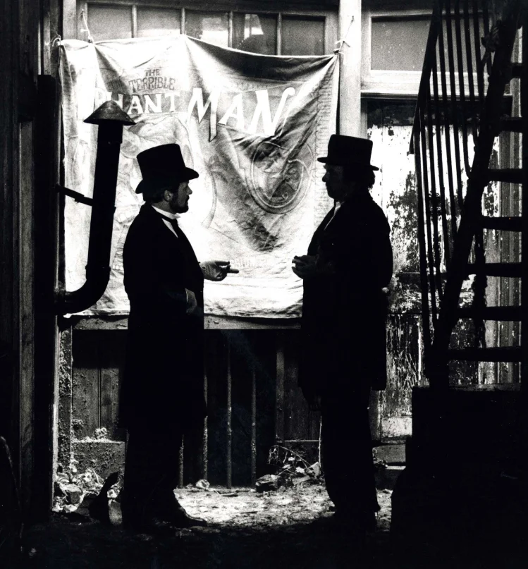 Spotlight-0626-14-Pressbook Dr. Treves (Anthony Hopkins) and Mr. Bytes (Freddie Jones) outside of Bytes’s freak show. Source: THE ELEPHANT MAN press book, Stuart Cornfeld Collection, AFI Archive.